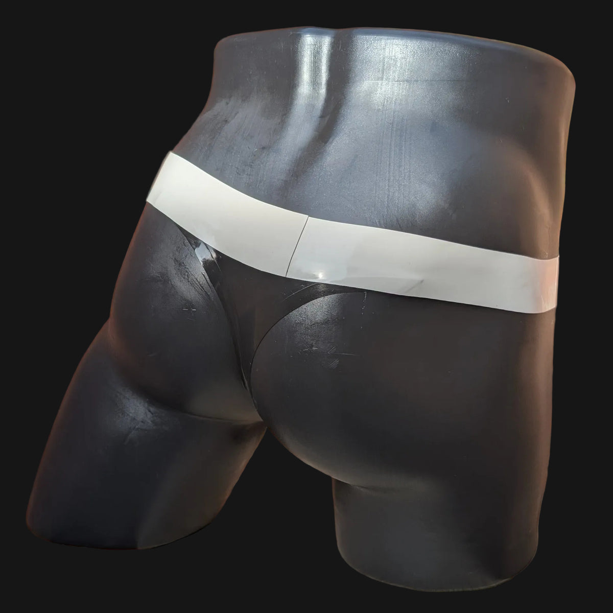 A black male mannequin torso wearing a black pair of briefs with a wide white waistband